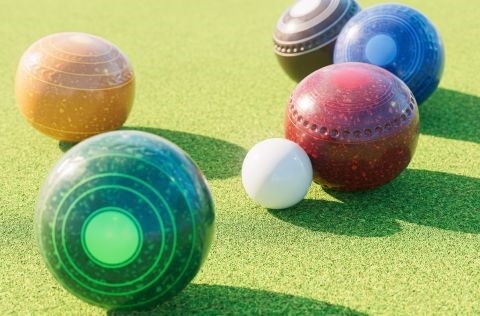 Different coloured lawn bowls on grass. 